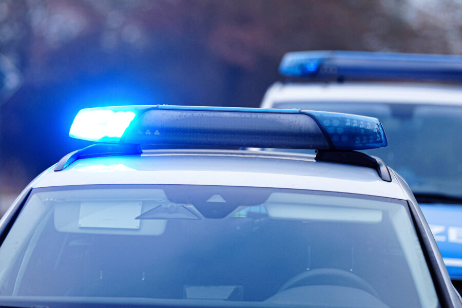 Polizeiauto mit blauem Licht auf dem Dach, unscharfes Fahrzeug im Hintergrund.