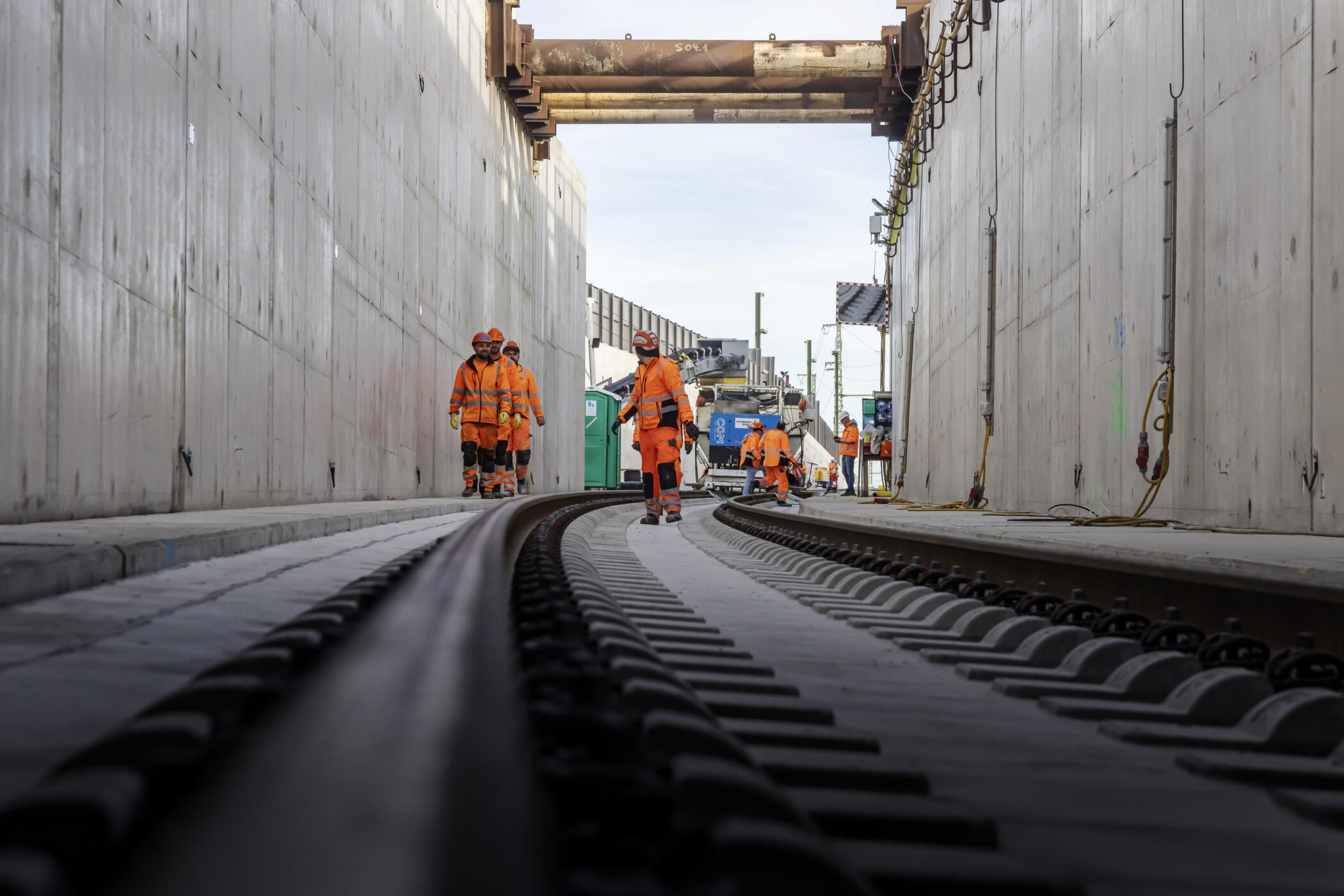 Bauarbeiter in orange Kleidung arbeiten in einem Eisenbahntunnel.