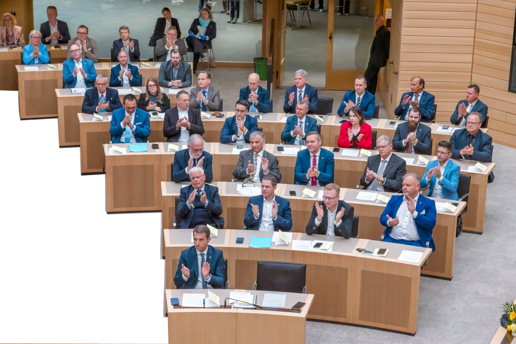 Mehrere Menschen sitzen in einem Raum und applaudieren.