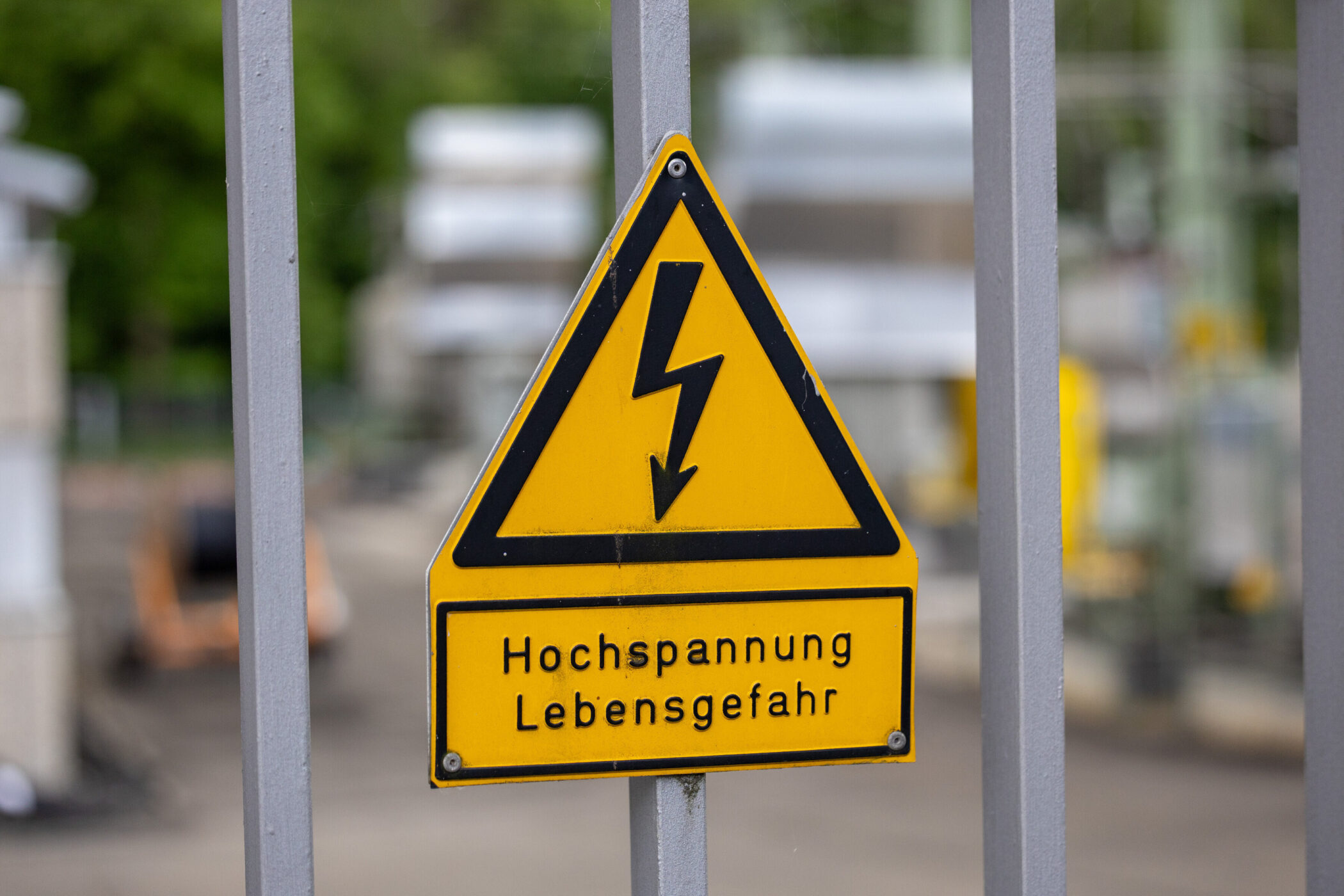 Gelbes Warnschild mit schwarzem Blitz, Text: "Hochspannung Lebensgefahr".