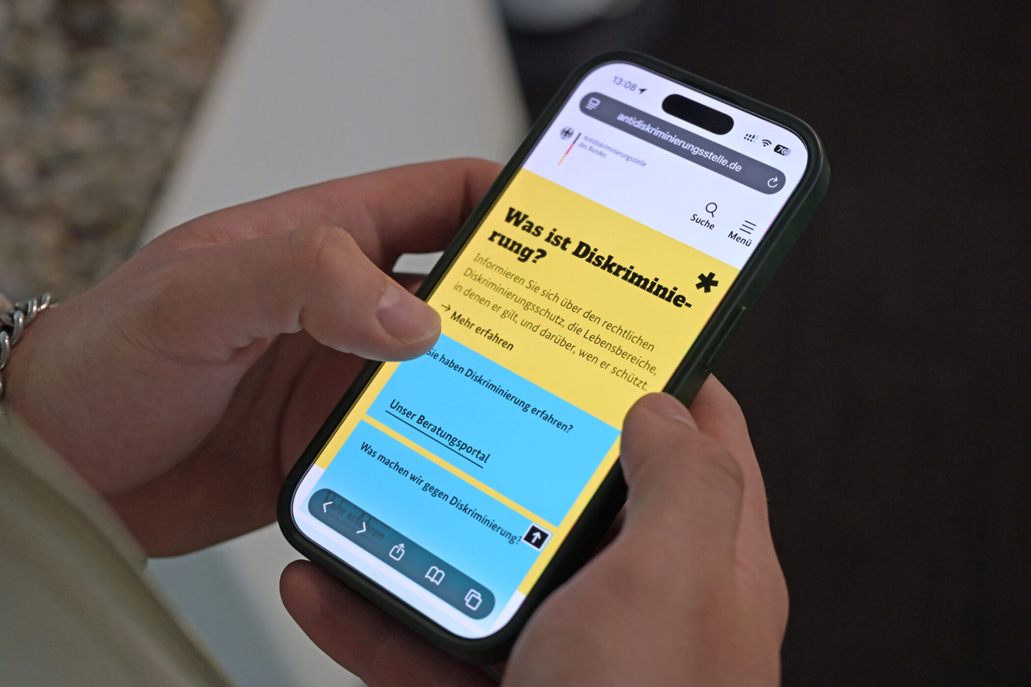 Zwei Hände halten ein Smartphone mit einer Webseite über Diskriminierungsschutz.