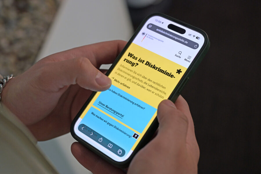 Zwei Hände halten ein Smartphone mit einer Webseite über Diskriminierungsschutz.