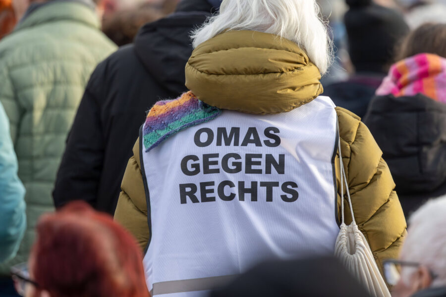 Person in gelber Jacke, trägt Weste mit Schrift "OMAS GEGEN RECHTS".
