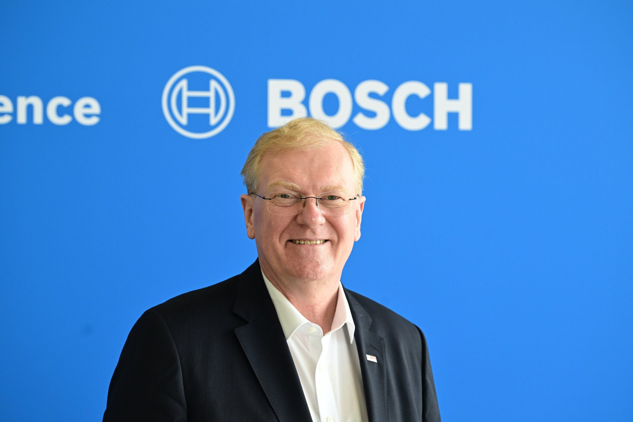 Mann in Anzug vor blauem Hintergrund mit Bosch-Logo.