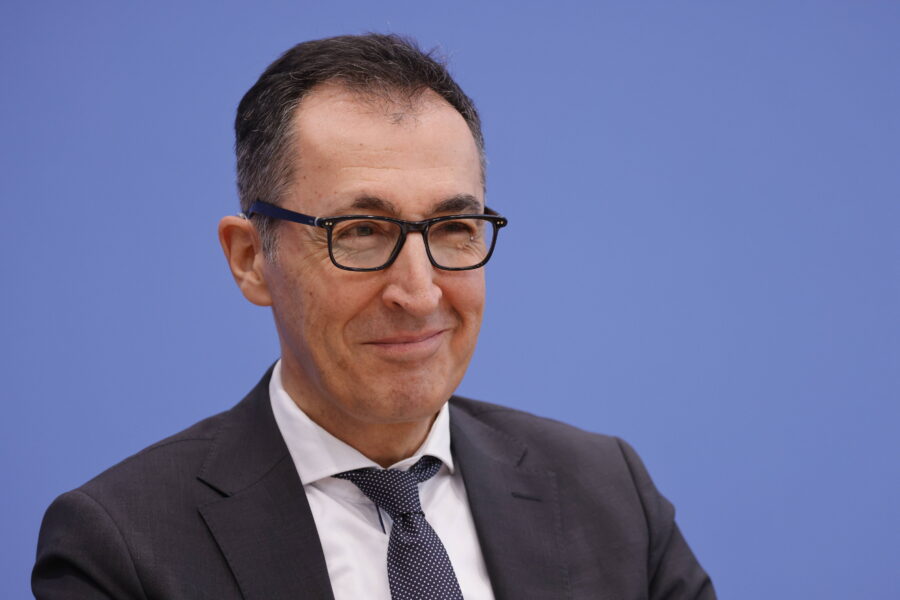 Person mit Brille und Anzug vor blauem Hintergrund.