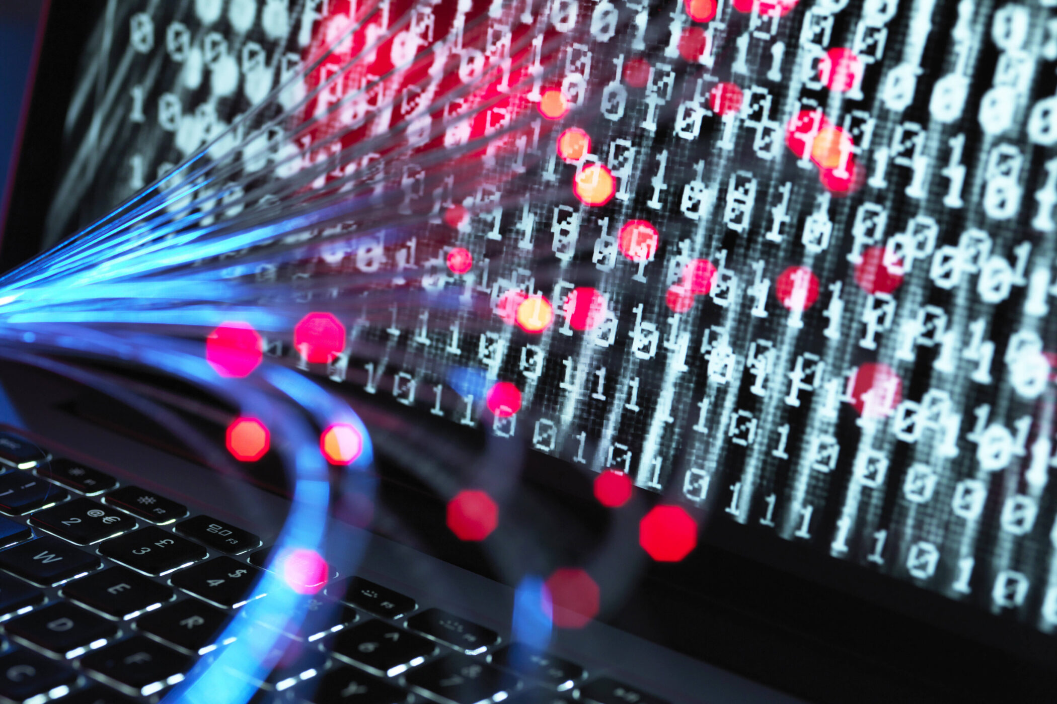 Laptop-Tastatur mit leuchtenden Datenströmen und Binärzahlen auf dem Bildschirm.