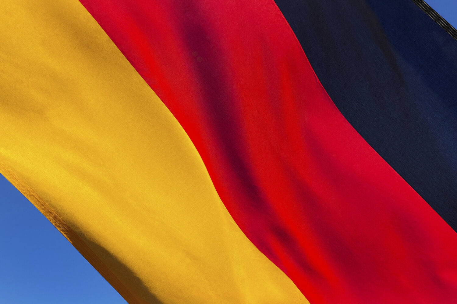 Dreifarbige Flagge: Schwarz, Rot, Gold auf blauem Hintergrund.