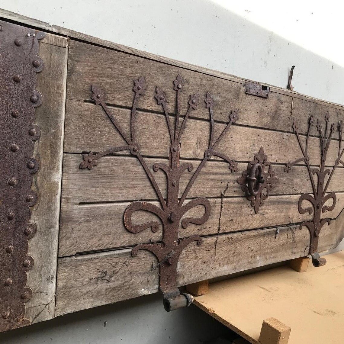 Holztür mit rostigen Metallverzierungen und Beschlägen.