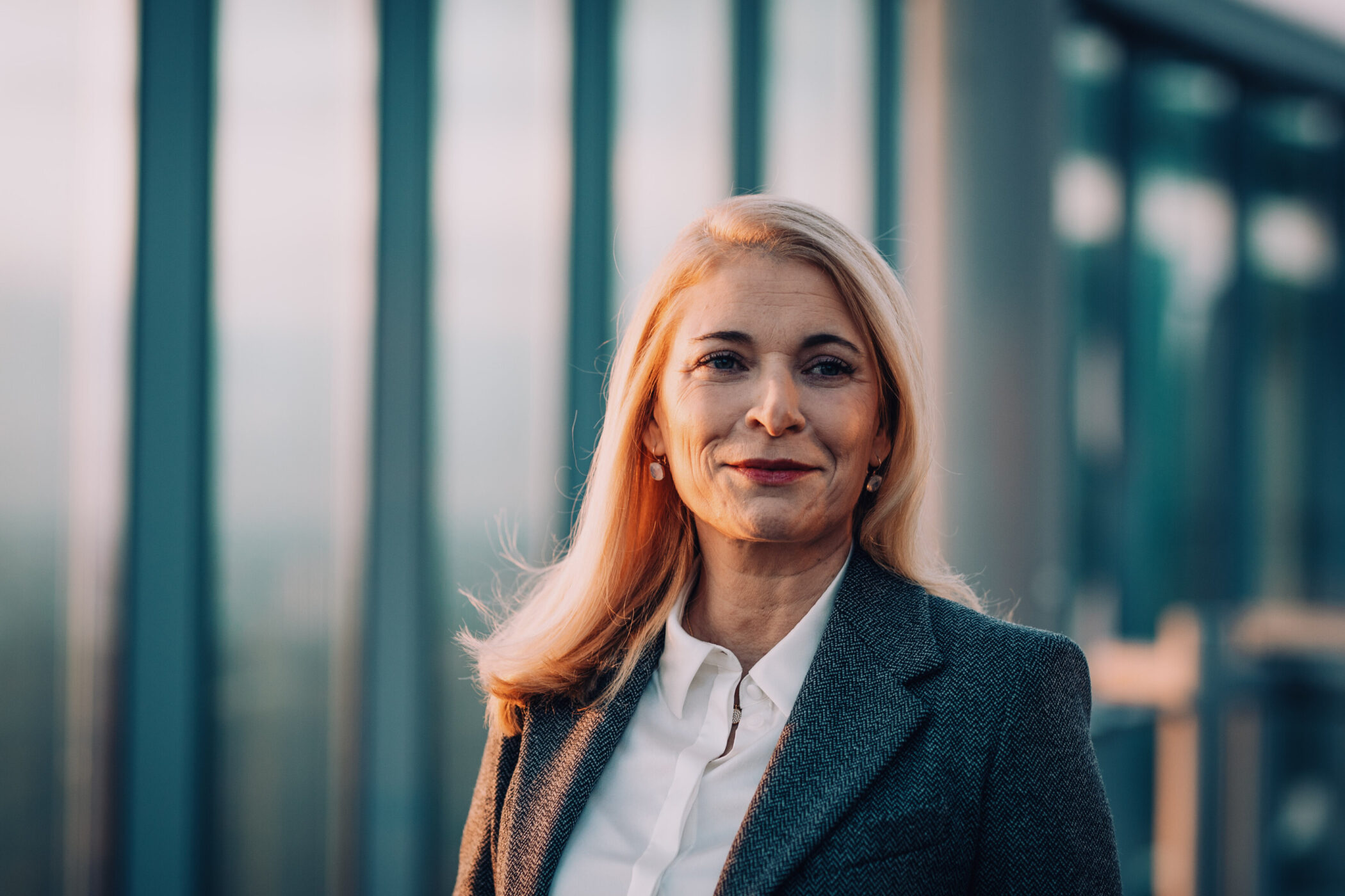Eine Person mit langen blonden Haaren steht vor Glasstrukturen.