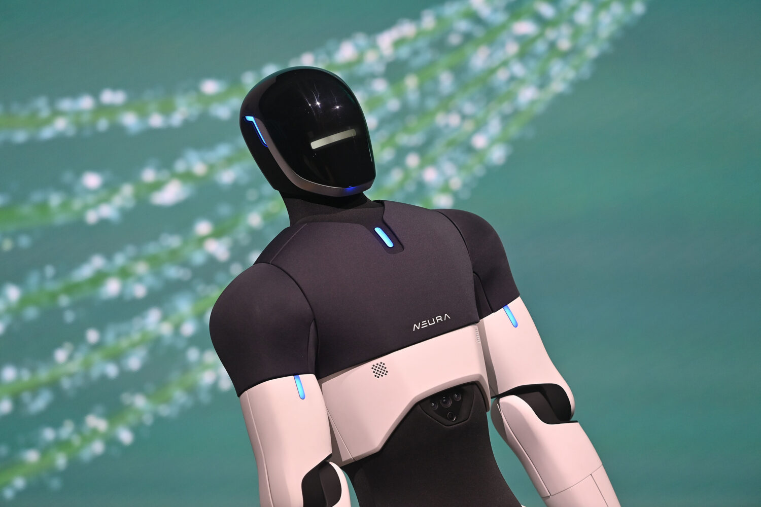 Roboter mit schwarzem Kopf und weißen Armen vor unscharfem Hintergrund.