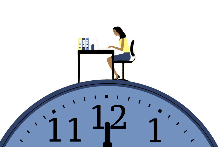 Frau sitzt am Schreibtisch auf einer Uhr, arbeitet am Laptop.
