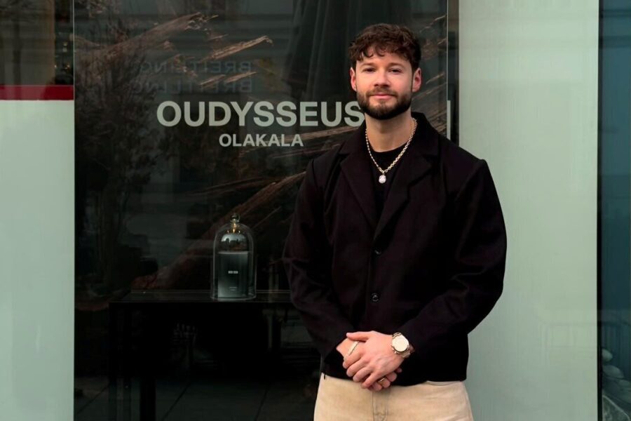 Zwei Menschen vor einem Schaufenster. Text: "OUDYSSEUS OLAKALA".