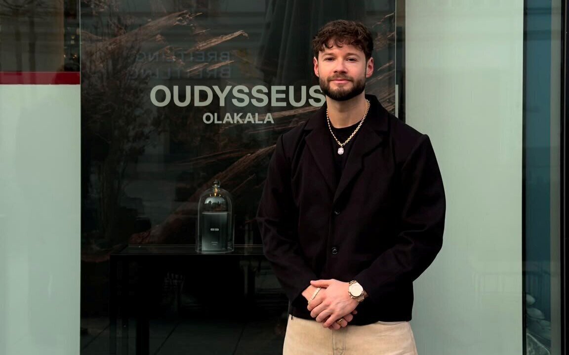 Zwei Menschen vor einem Schaufenster. Text: "OUDYSSEUS OLAKALA".