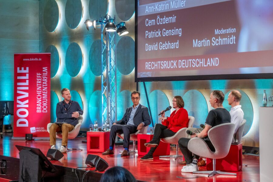 Fünf Personen diskutieren auf einer Bühne; Hintergrund mit Schrift: "RECHTSRUCK DEUTSCHLAND".
