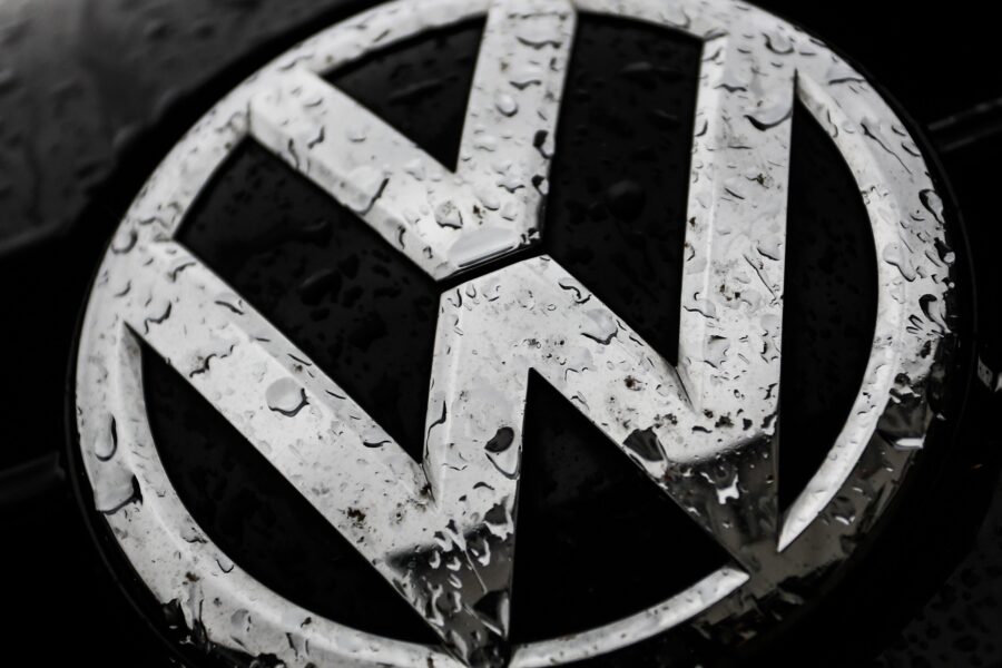 Silbernes VW-Logo mit Wassertropfen bedeckt auf dunklem Hintergrund.