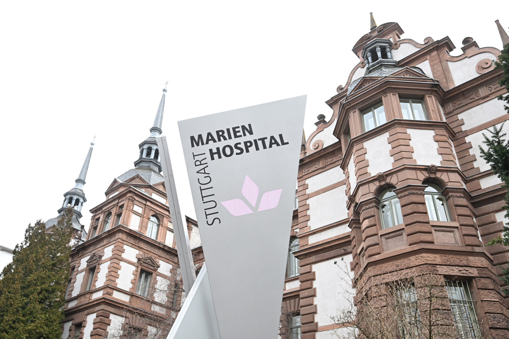 Zwei Spitztürme und Schild: "Marien Hospital Stuttgart" vor historischem Gebäude.