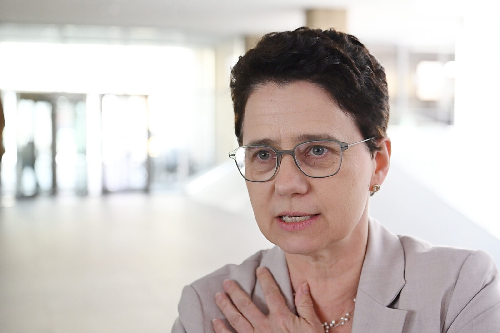 Frau mit Brille und kurzem Haar in einem hellen Raum.