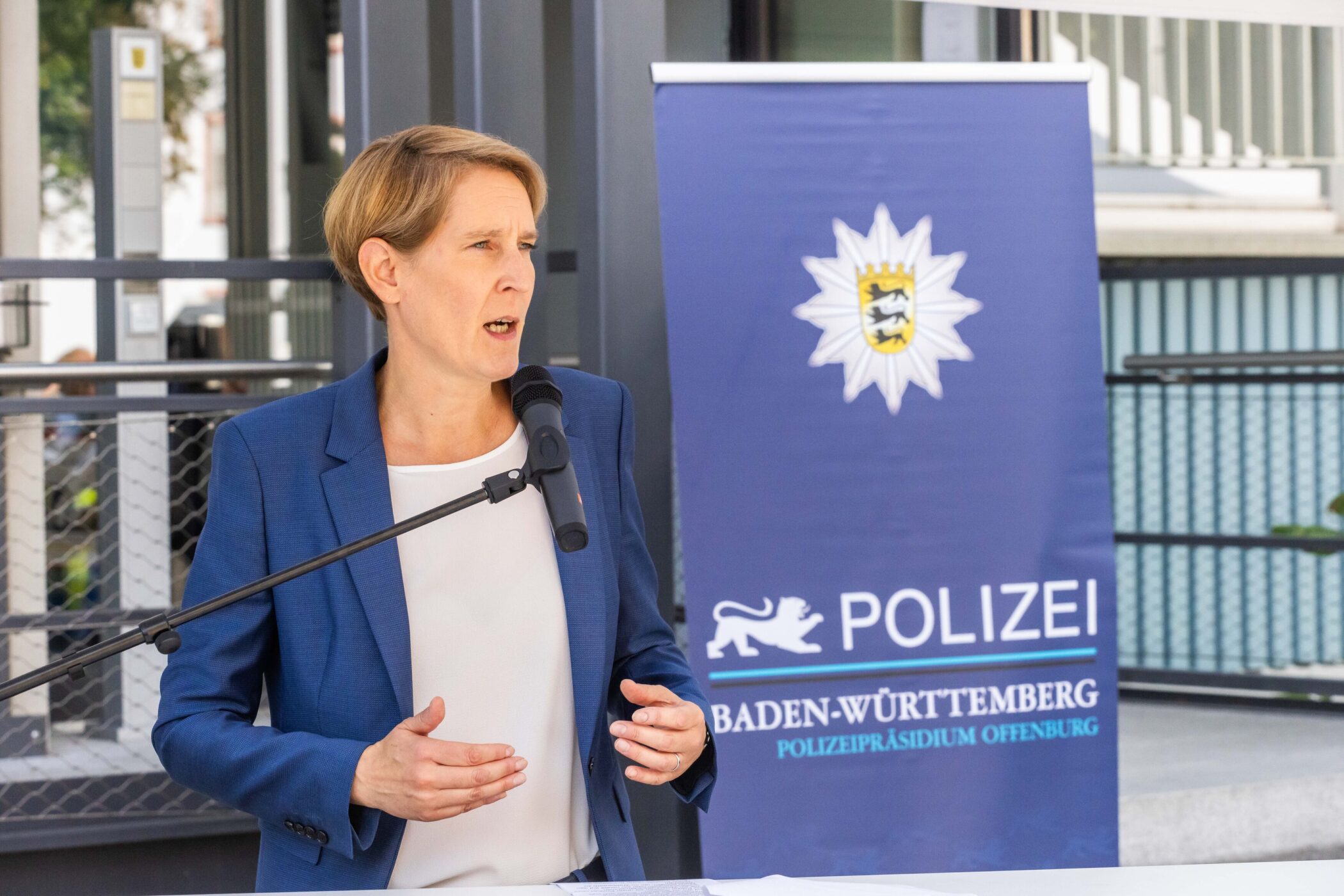Eine Frau spricht, Banner mit Text: "Polizei Baden-Württemberg".