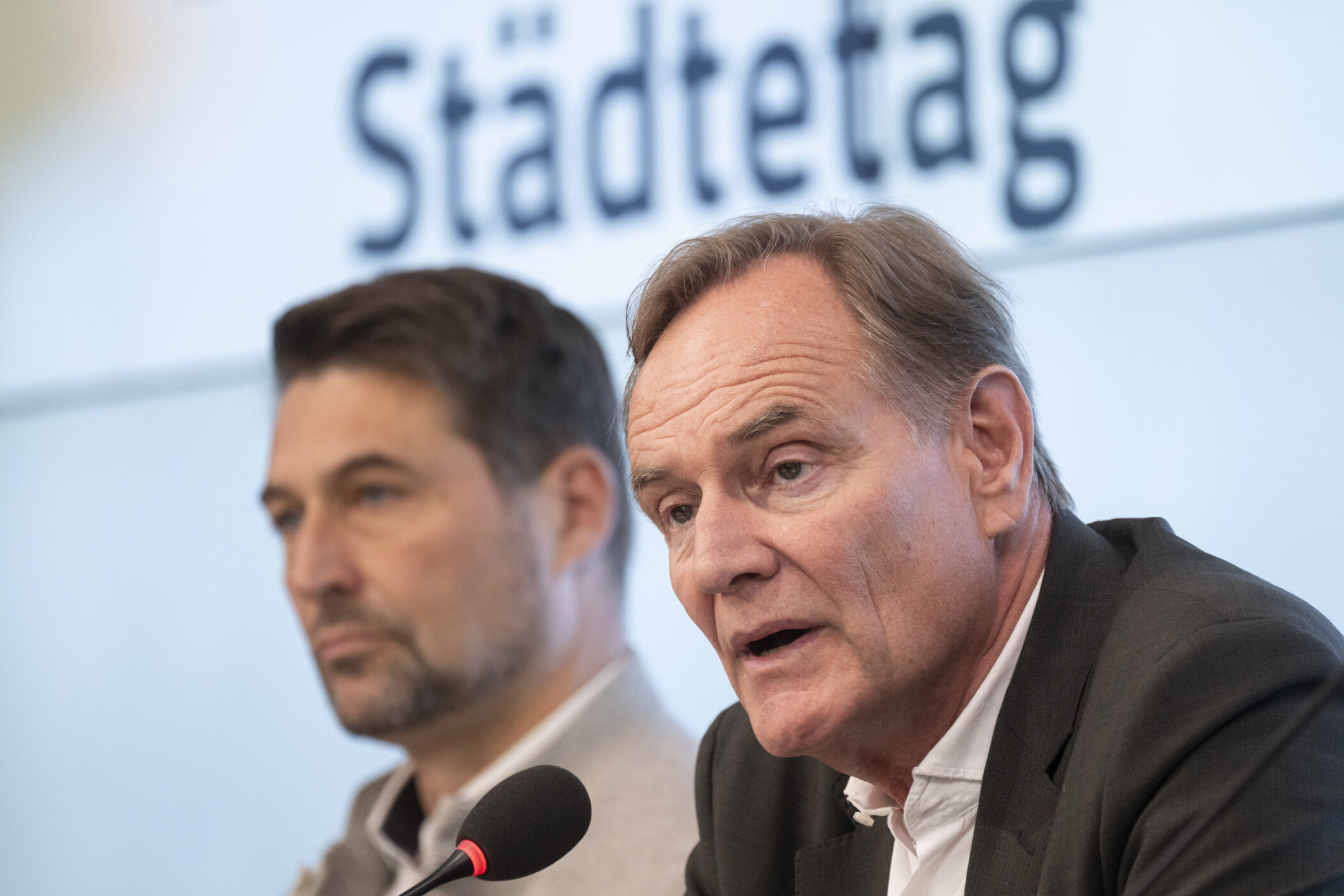 Zwei Männer an Mikrofonen, im Hintergrund Schriftzug "Städtetag".