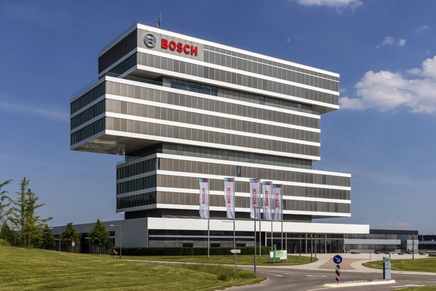 Modernes Gebäude mit "Bosch"-Logo und Fahnen davor, blauer Himmel im Hintergrund.