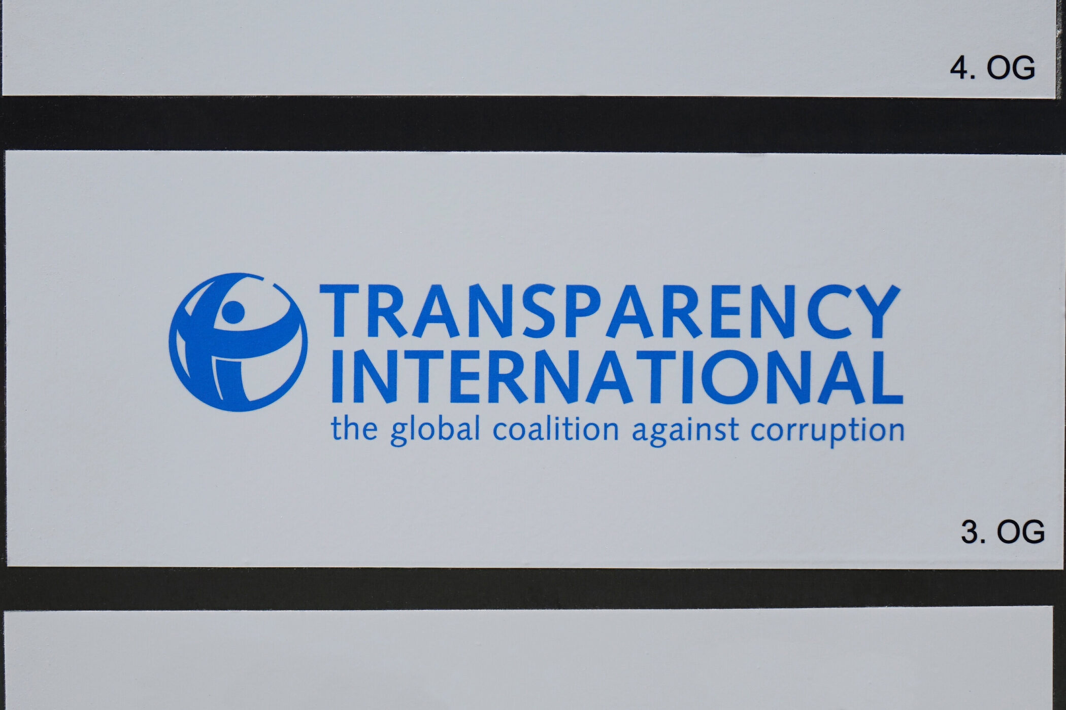 Transparenz International-Logo mit Text "the global coalition against corruption". 3. OG.
