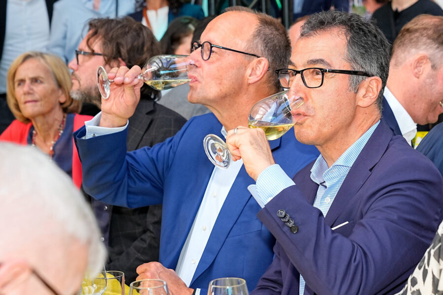 Menschen bei einer Veranstaltung trinken Weißwein aus Weingläsern.
