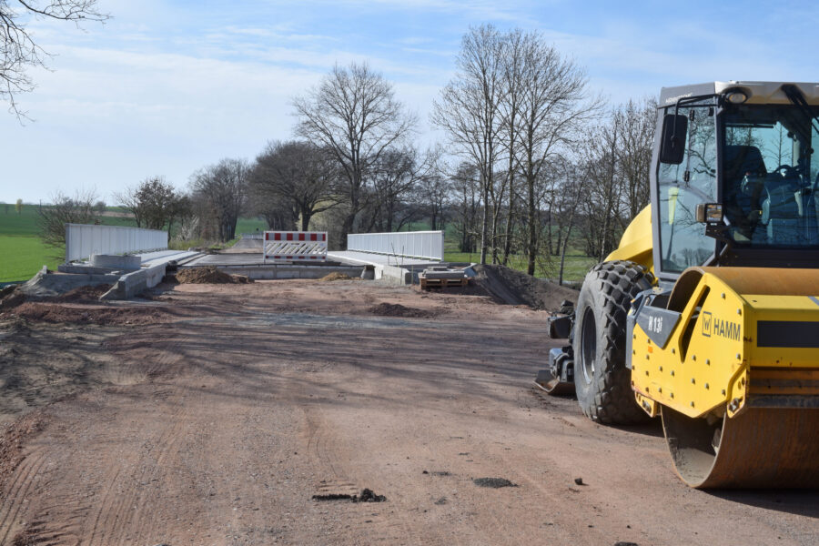 Baustelle mit gelber Walze und einer teilweise fertigen Straße im Freien.
