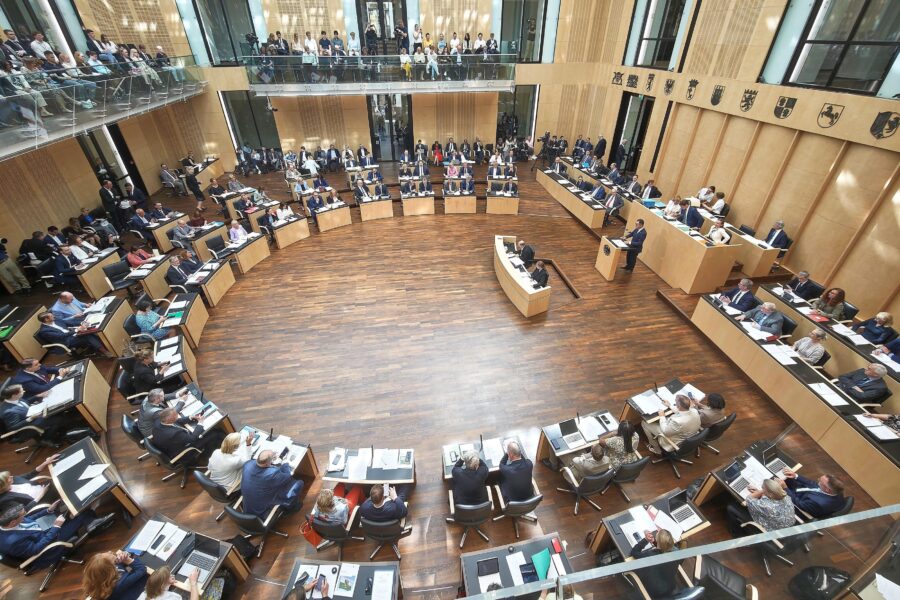 Geräumiger Sitzungssaal, viele Personen an Tischen, ein Redner am Pult.