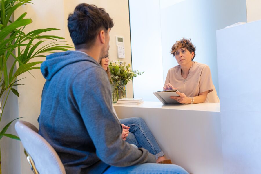 Drei Personen sitzen an einem Tisch, eine Person hält ein Tablet.