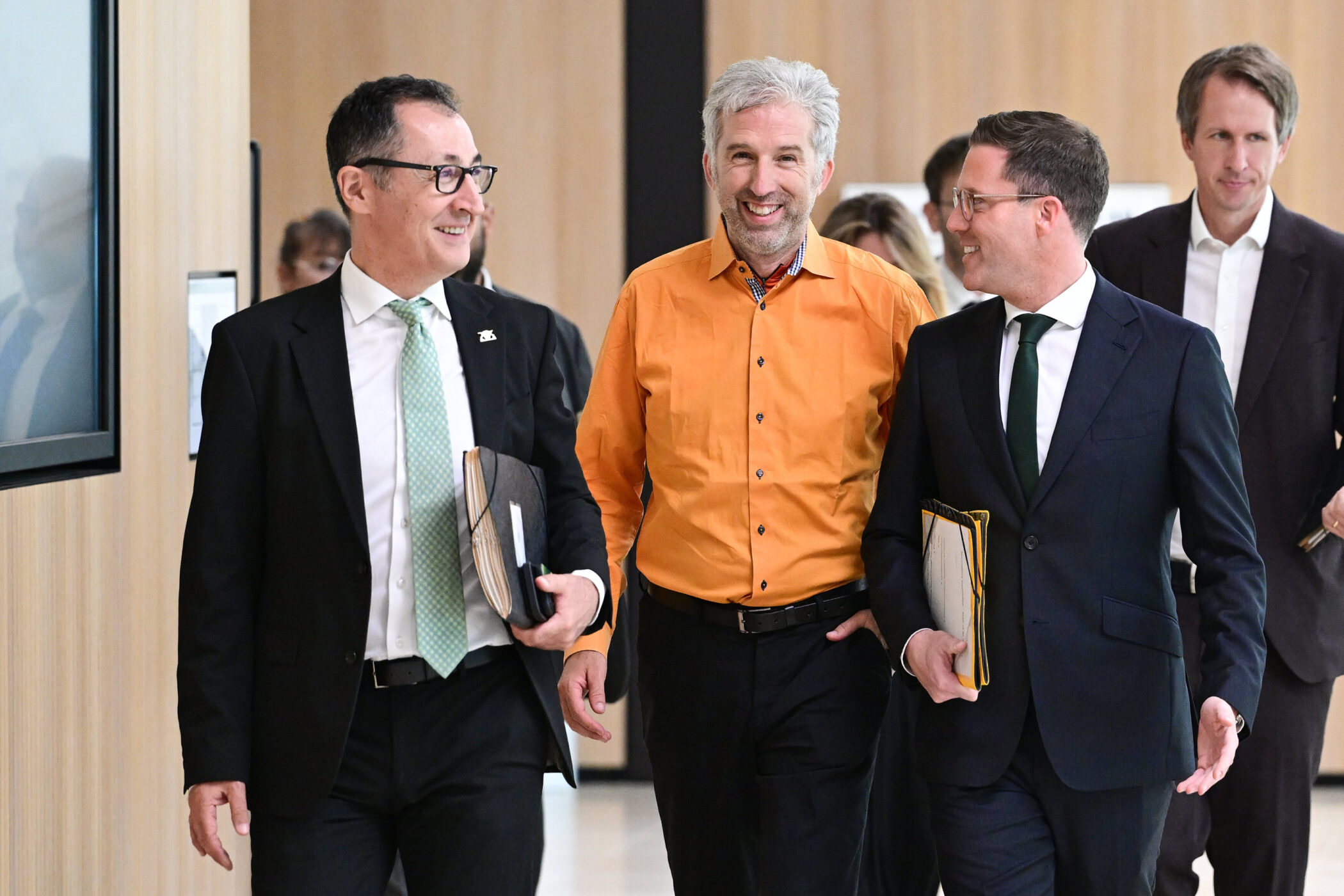 Fünf Männer in Anzügen und Hemden gehen und unterhalten sich.