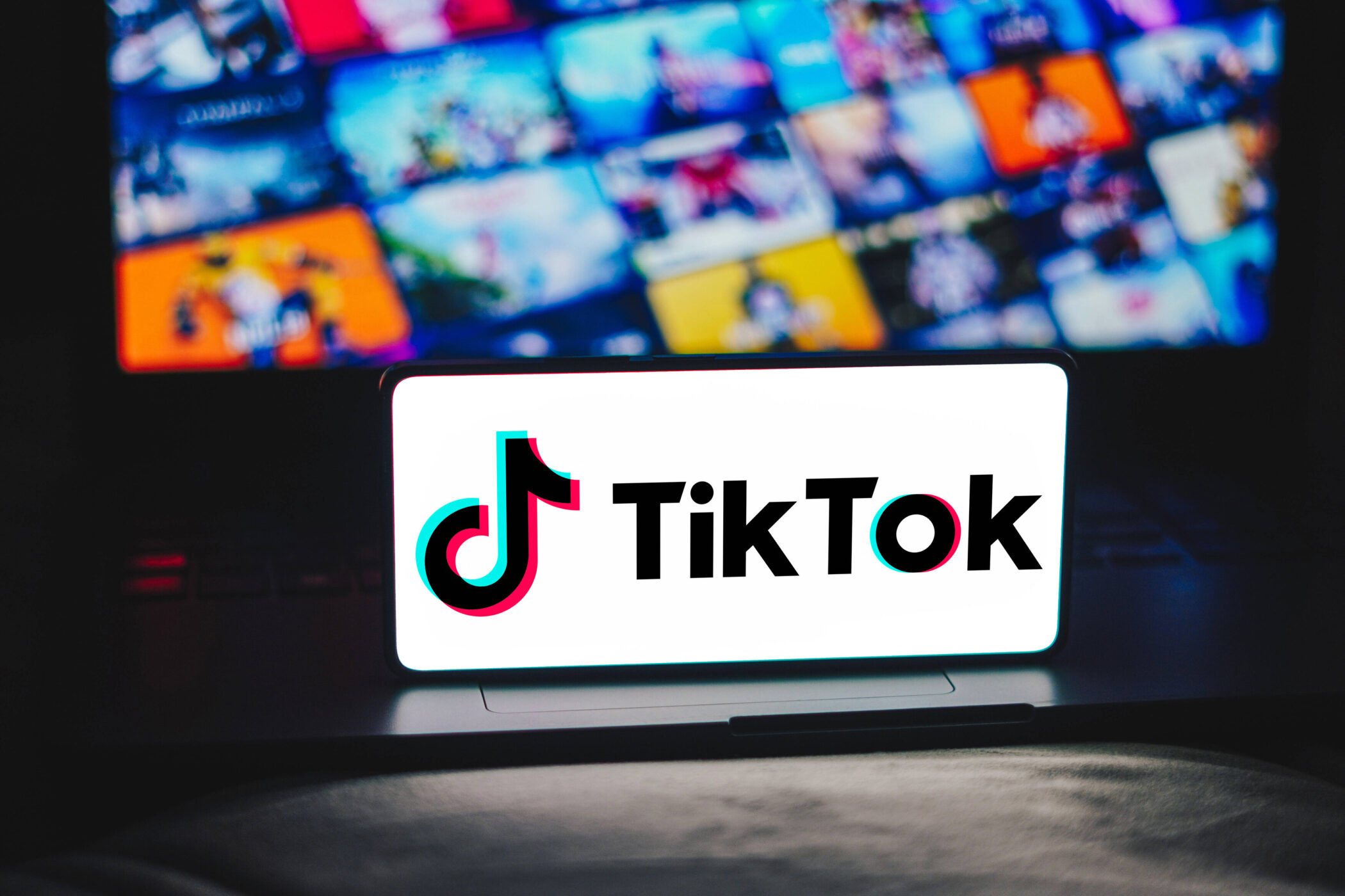 Ein TikTok-Logo auf einem Bildschirm, Hintergrund unscharfe bunte Bilder.