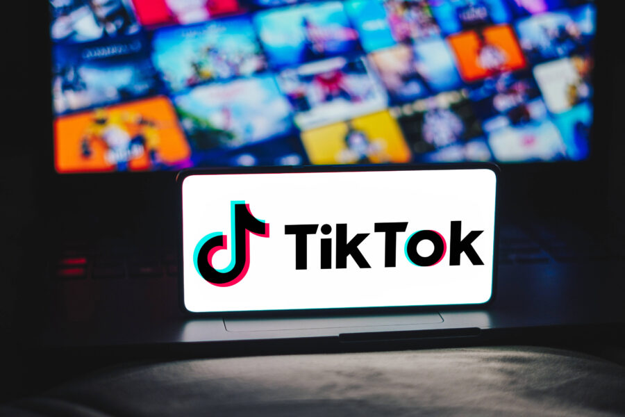 Ein TikTok-Logo auf einem Bildschirm, Hintergrund unscharfe bunte Bilder.
