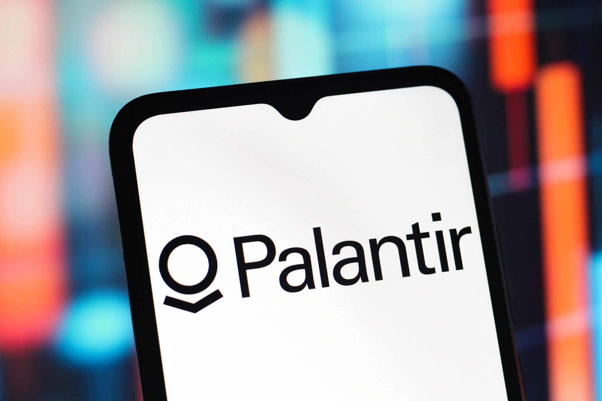 Schriftzug "Palantir" auf Smartphone-Bildschirm, unscharfer bunter Hintergrund.