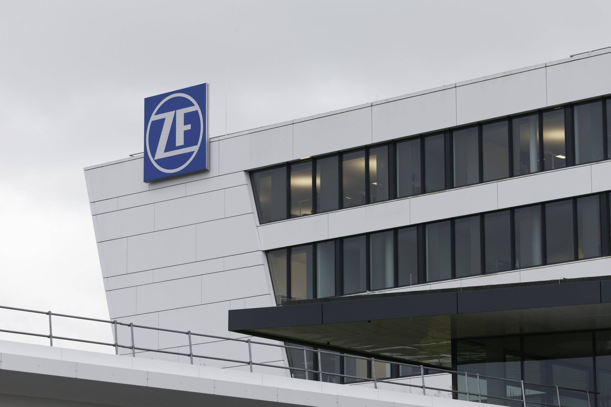 Modernes Gebäude mit ZF-Logo und großen Glasfenstern unter grauem Himmel.