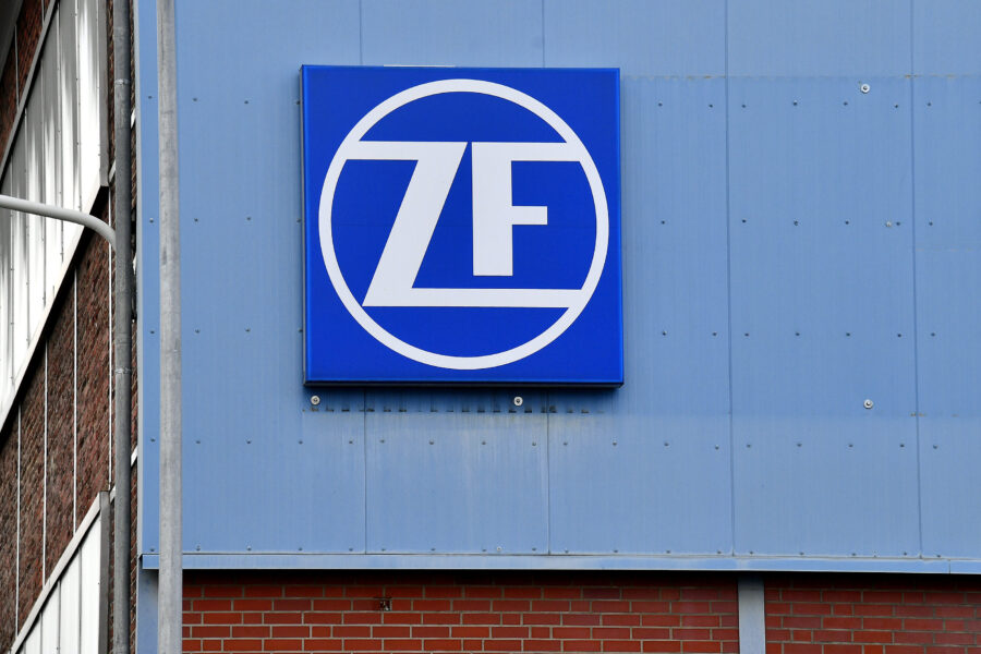 Blaues Firmenschild mit weißem "ZF" auf einer grauen Gebäudewand.