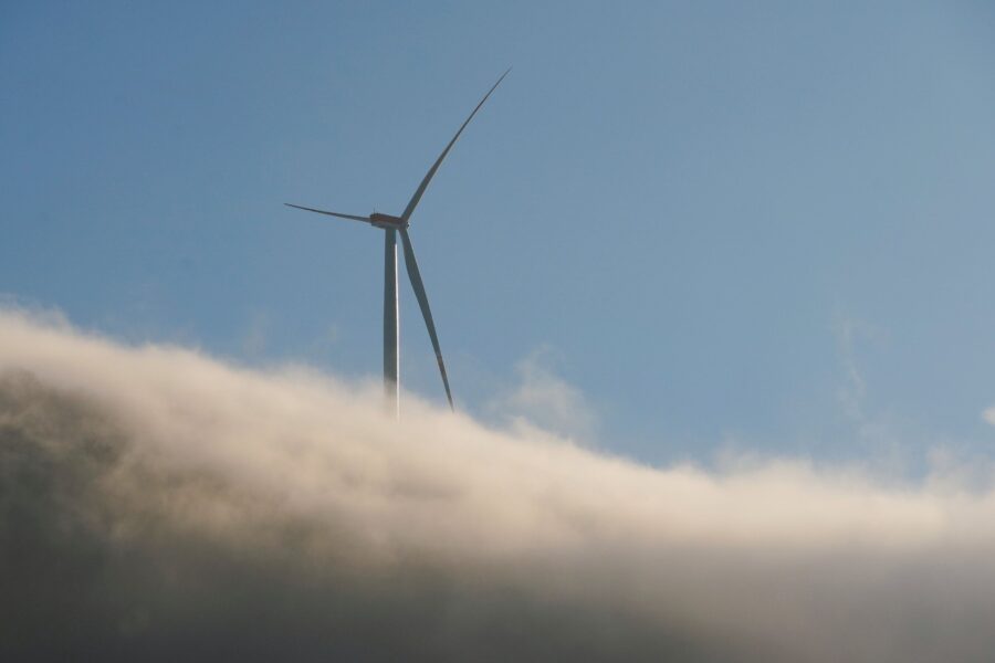 Windradspitze ragt über Wolken in blauem Himmel hervor.