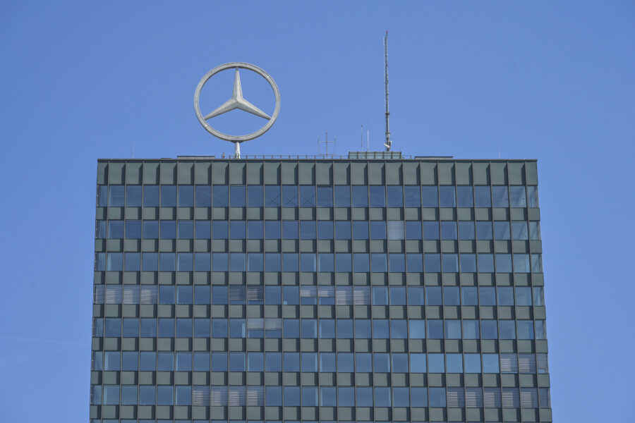 Hochhaus mit Mercedes-Stern auf dem Dach, blauer Himmel im Hintergrund.
