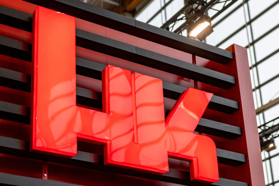 Rotes „HK“-Logo auf schwarzem Hintergrund mit Streben.