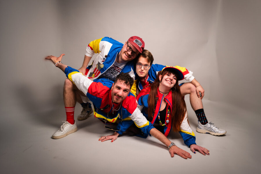 Vier Personen in bunter Sportkleidung posieren lachend im Fotostudio.