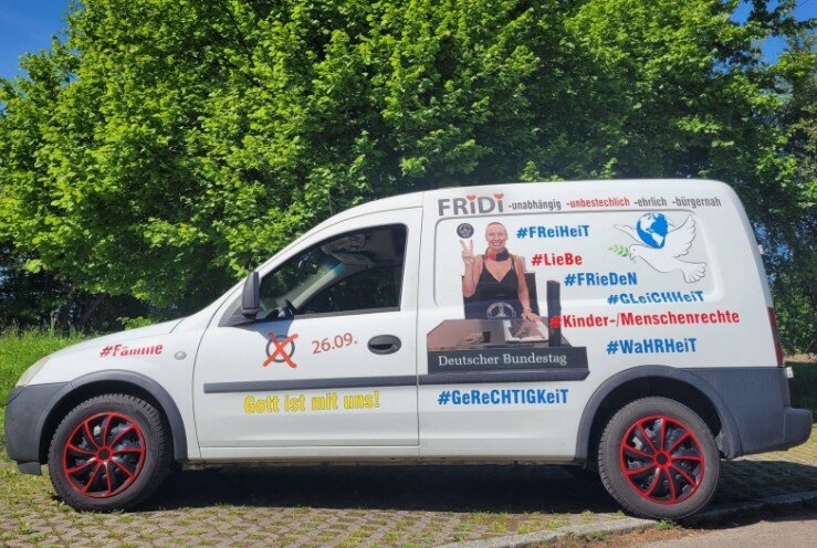 Weißer Lieferwagen mit Schriftzügen, Hashtags und Symbolen, steht auf Kopfsteinpflaster.