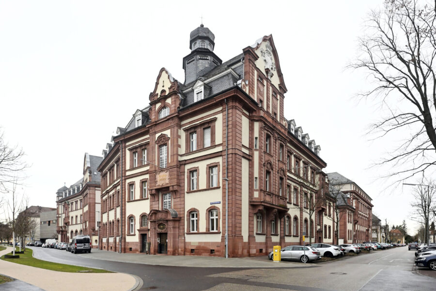 Großes, historisches Gebäude an Straßenecke, Autos parken entlang der Straße.