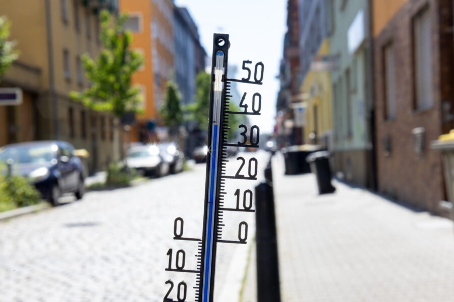 Thermometer zeigt 30 Grad, verschwommene Straße im Hintergrund.