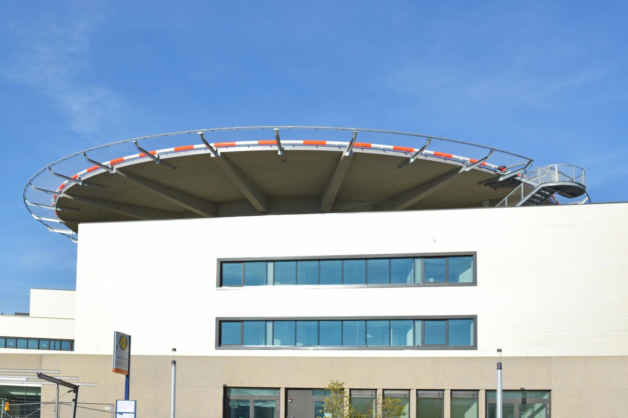 Modernes Gebäude mit einem Hubschrauberlandeplatz auf dem Dach und blauer Himmel.