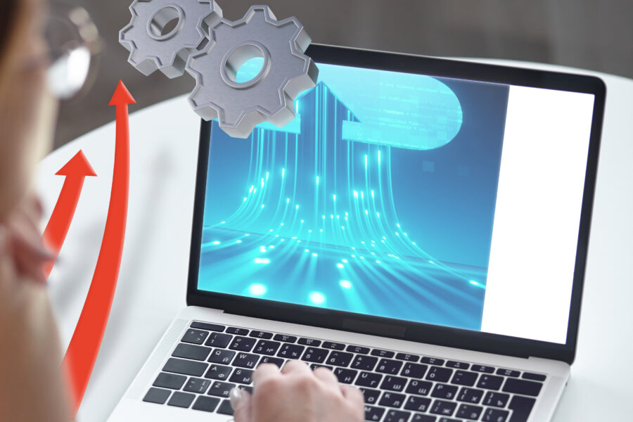 Person bei Laptop mit digitaler Grafik und Zahnrädern auf dem Bildschirm.