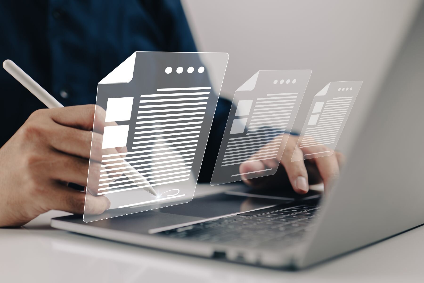 Person schreibt mit Stift auf Laptop mit schwebenden digitalen Dokumenten.