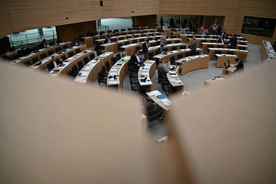 Großer Sitzungssaal mit vielen Tischen, einige Menschen verteilt sitzend und stehend.