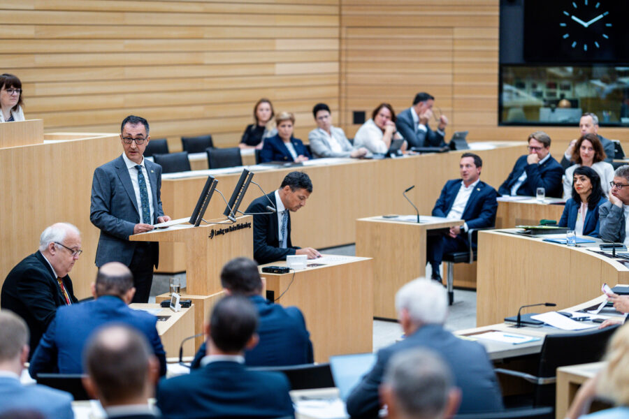 Mehrere Personen in einem Sitzungssaal, eine spricht am Rednerpult.