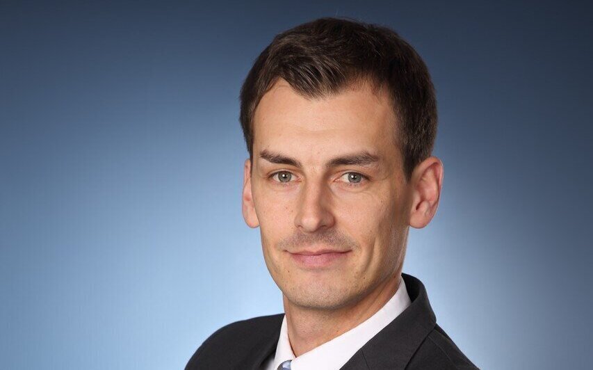 Mann in Anzug vor blauem Hintergrund.