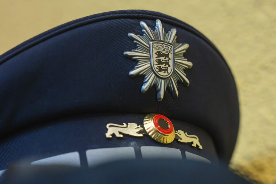 Schwarze Polizeimütze mit silbernem Abzeichen und roten Akzenten.