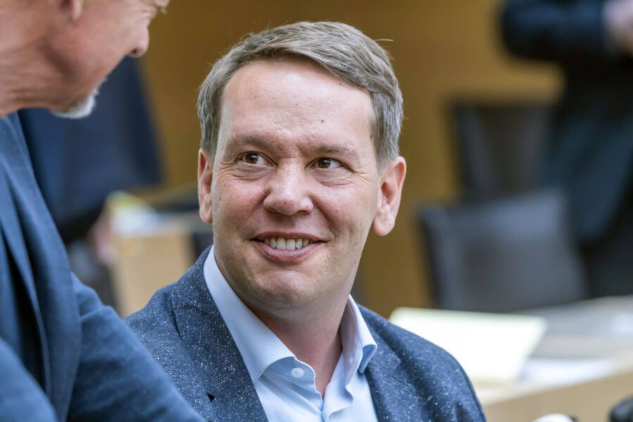 Zwei Männer im Gespräch in einem Raum mit unscharfem Hintergrund.